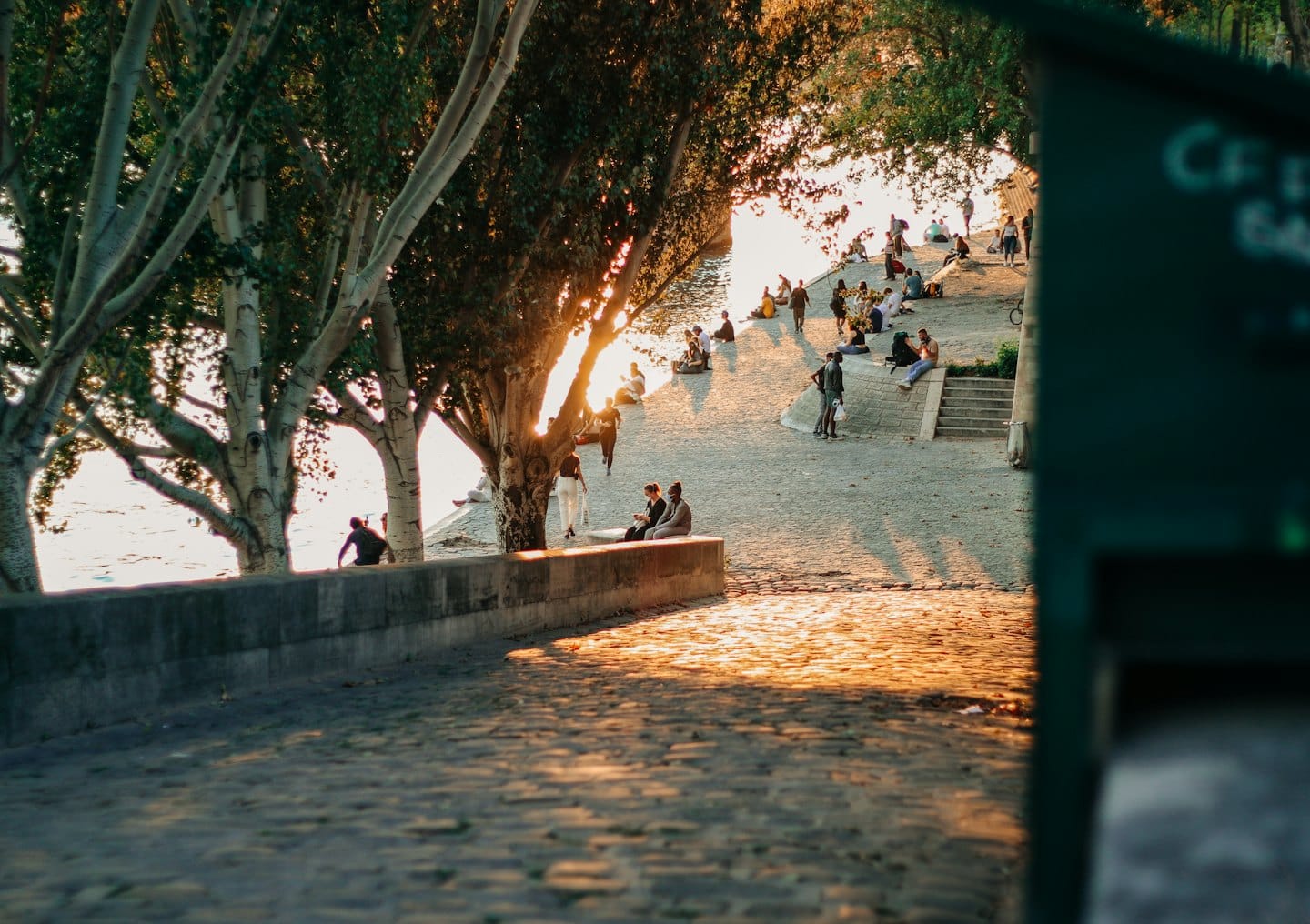 Persone diverse si rilassano e passeggiano lungo un fiume all'ora d'oro.